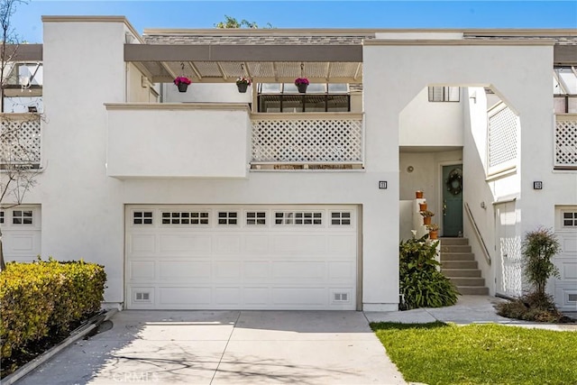 view of front of house featuring a garage, concrete driveway, and stucco siding