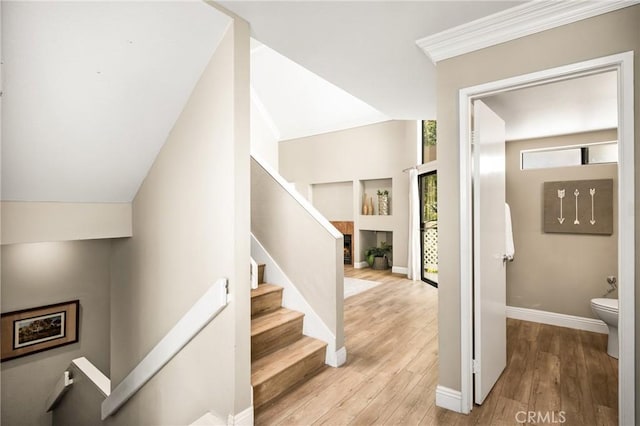 stairway featuring a fireplace, baseboards, and wood finished floors