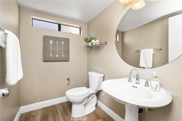 bathroom with a sink, wood finished floors, toilet, and baseboards