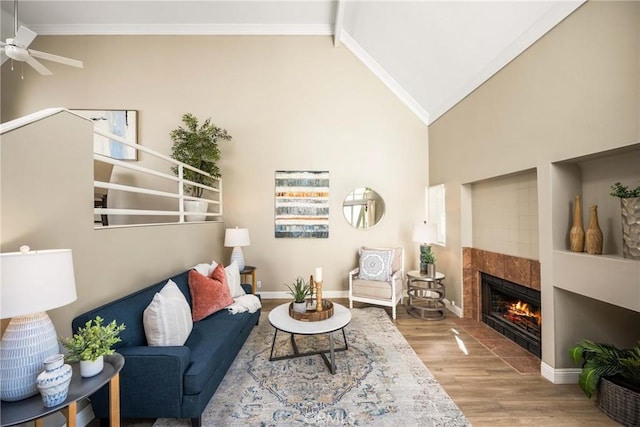 living area with high vaulted ceiling, baseboards, ornamental molding, and wood finished floors