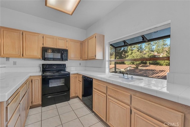 kitchen with light countertops, light brown cabinets, a sink, light tile patterned flooring, and black appliances