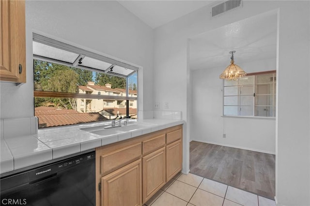 kitchen featuring tile counters, visible vents, dishwasher, an inviting chandelier, and a sink