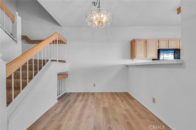 unfurnished dining area featuring light wood-type flooring, baseboards, a chandelier, and stairs