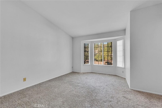 spare room featuring carpet flooring and baseboards