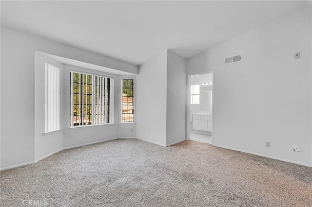 empty room featuring a healthy amount of sunlight, baseboards, visible vents, and carpet flooring