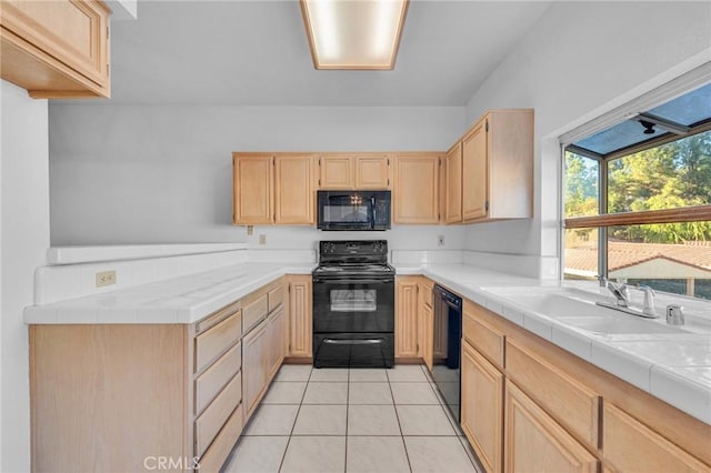 kitchen with a sink, black appliances, and light brown cabinetry