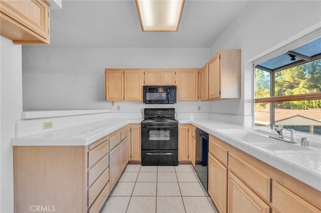 kitchen with light brown cabinets, a sink, black appliances, and light tile patterned flooring