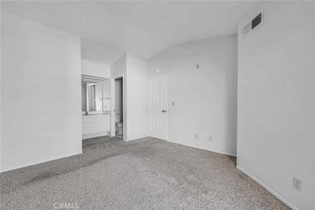 empty room with baseboards, vaulted ceiling, visible vents, and carpet