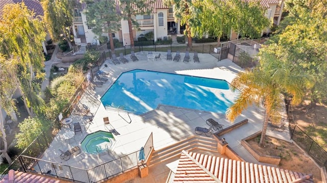 community pool featuring a patio area, fence, and a hot tub