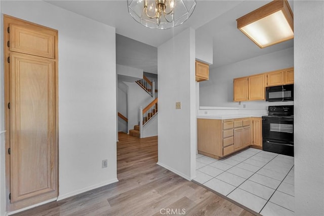 kitchen featuring light countertops, light brown cabinets, light wood-type flooring, black appliances, and a notable chandelier