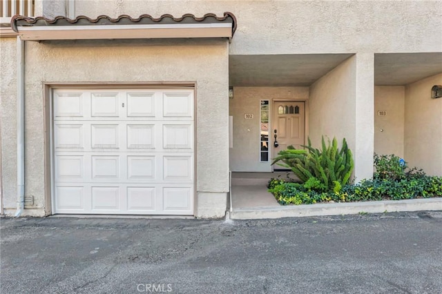 view of exterior entry featuring a garage and stucco siding
