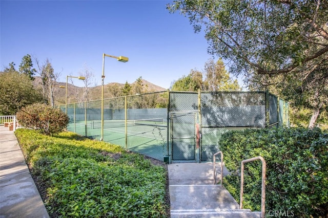 view of tennis court with a gate and fence