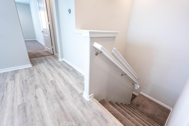 staircase featuring wood finished floors and baseboards