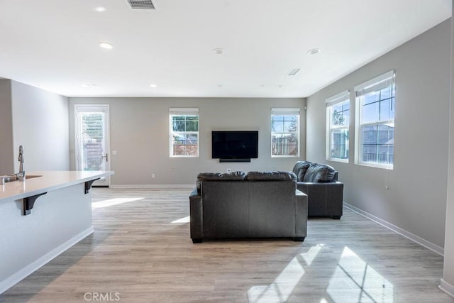 living room featuring light wood-style floors, recessed lighting, visible vents, and baseboards