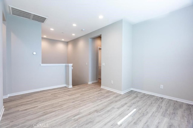 spare room featuring light wood-type flooring, visible vents, baseboards, and recessed lighting