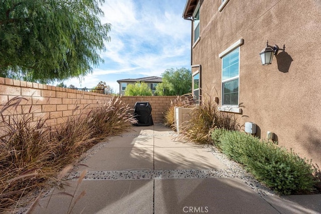 view of side of property with a patio, fence, and stucco siding