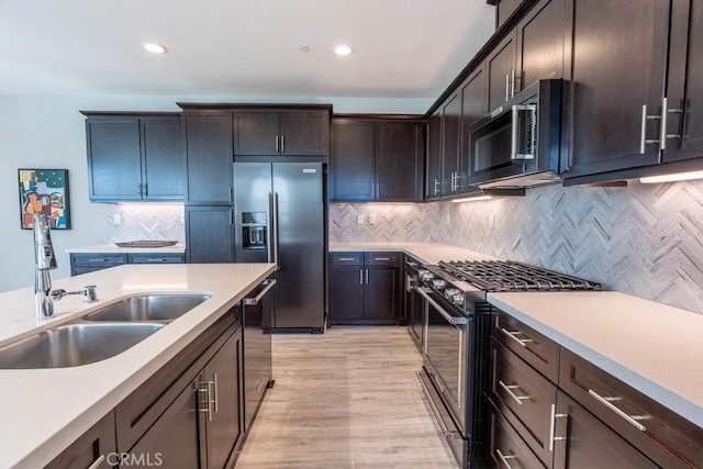 kitchen featuring light countertops, tasteful backsplash, high end appliances, and a sink