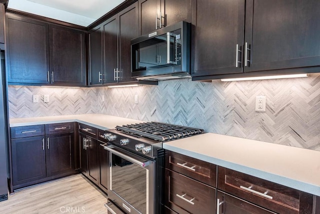 kitchen with stainless steel appliances, light countertops, light wood-style flooring, and backsplash