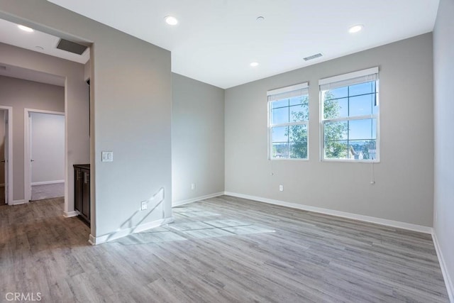 empty room with light wood-type flooring, baseboards, visible vents, and recessed lighting