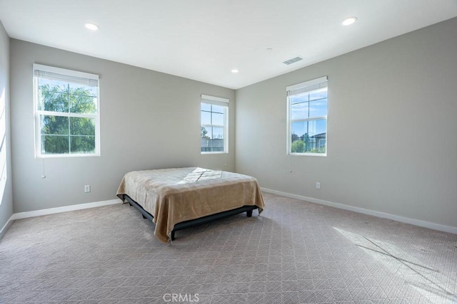 bedroom featuring baseboards, multiple windows, visible vents, and carpet flooring