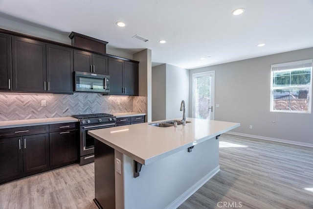 kitchen featuring appliances with stainless steel finishes, plenty of natural light, a sink, and an island with sink