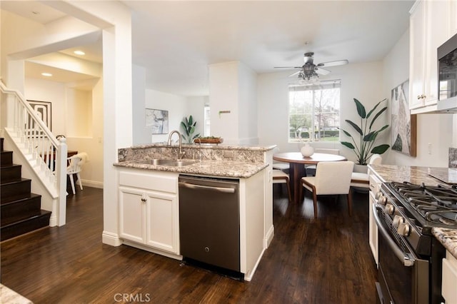 kitchen featuring stainless steel appliances, dark wood-type flooring, white cabinetry, a sink, and light stone countertops