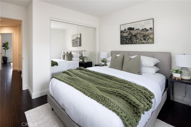 bedroom with a closet, baseboards, and wood finished floors