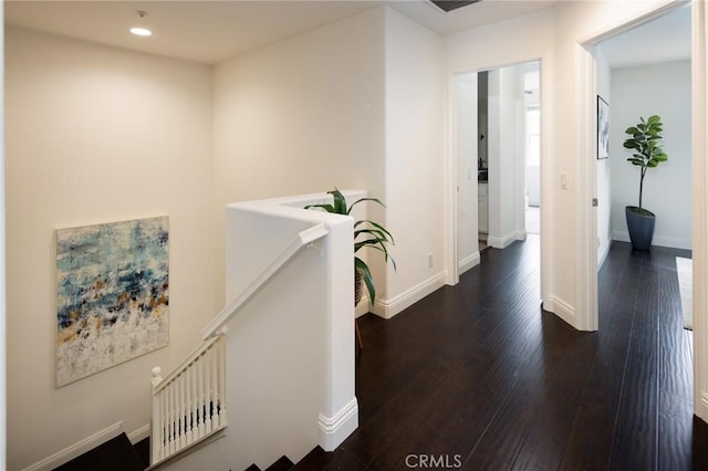 hall featuring recessed lighting, dark wood-style flooring, baseboards, and an upstairs landing