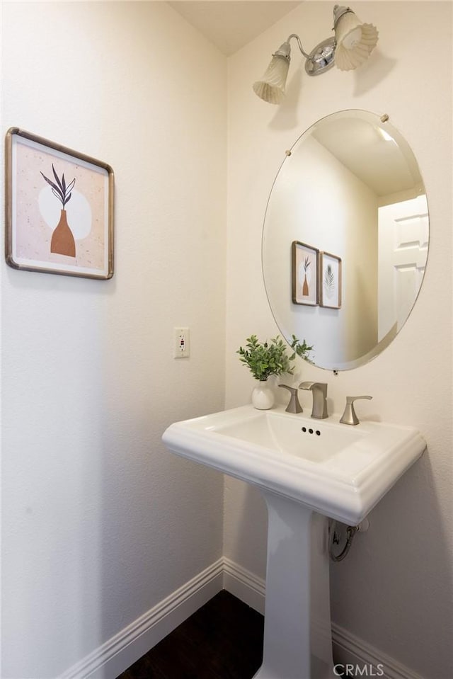 bathroom with wood finished floors, a sink, and baseboards