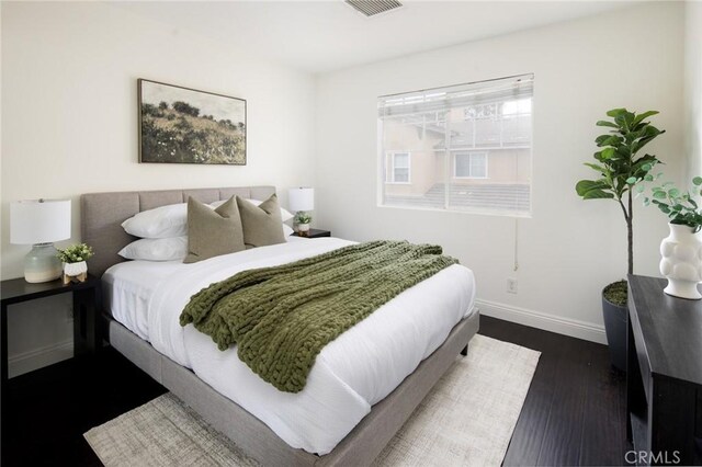 bedroom featuring dark wood finished floors, visible vents, and baseboards