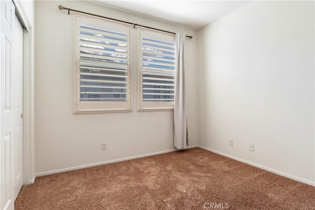 spare room featuring carpet and baseboards