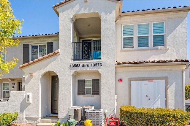 mediterranean / spanish-style home featuring a tiled roof, central AC unit, and stucco siding