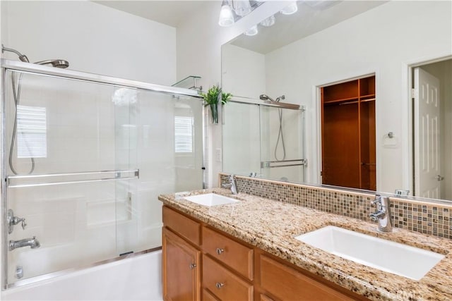 bathroom with tasteful backsplash, combined bath / shower with glass door, a sink, and double vanity