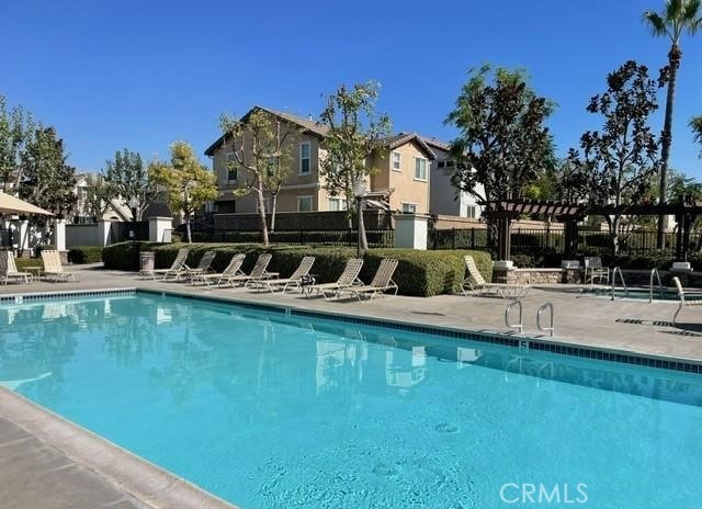 community pool with a patio, fence, a residential view, and a pergola