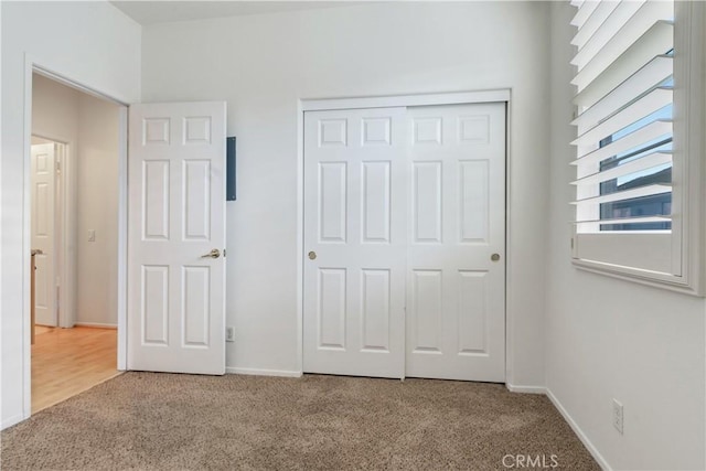 unfurnished bedroom featuring carpet, baseboards, and a closet