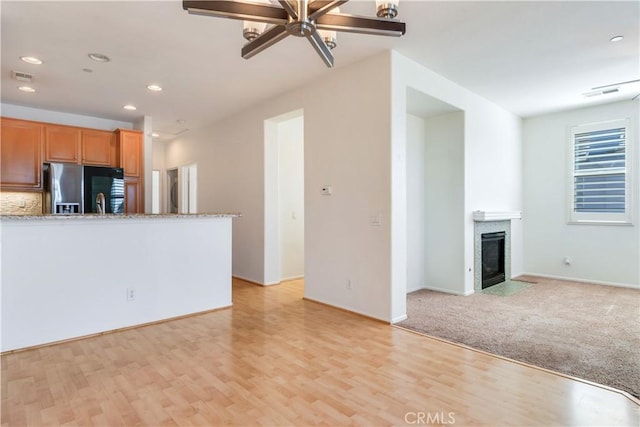 unfurnished living room featuring light wood-type flooring, a fireplace with flush hearth, visible vents, and recessed lighting