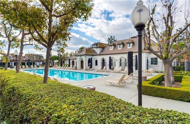 pool with a patio area and fence