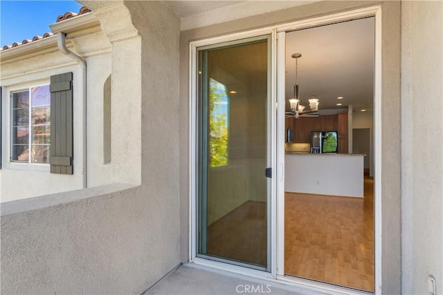 property entrance featuring a tiled roof and stucco siding