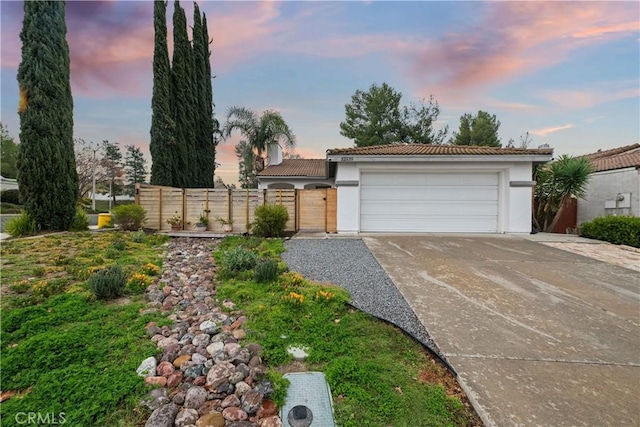 view of front of home with a gate, stucco siding, concrete driveway, a garage, and a tiled roof