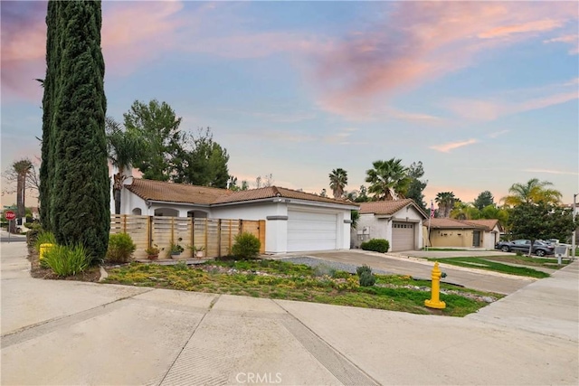 ranch-style home with a fenced front yard, driveway, an attached garage, and stucco siding