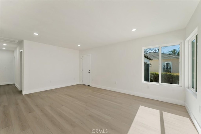 empty room featuring light wood finished floors, baseboards, and recessed lighting