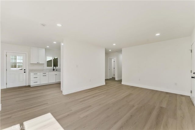 unfurnished living room featuring baseboards, light wood finished floors, and recessed lighting