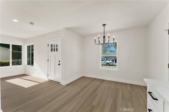 unfurnished dining area with light wood finished floors, baseboards, a chandelier, and recessed lighting