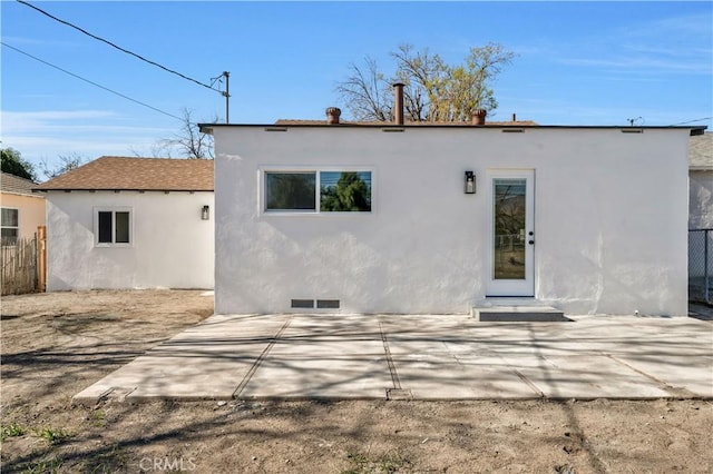 rear view of property featuring visible vents, a patio, fence, and stucco siding