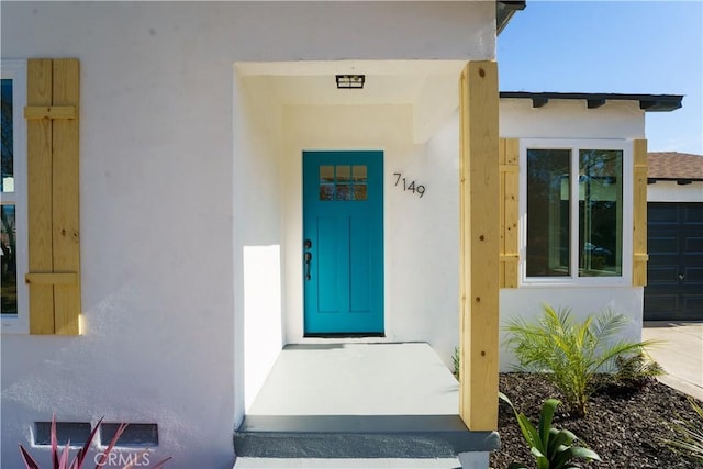 doorway to property featuring a garage and stucco siding