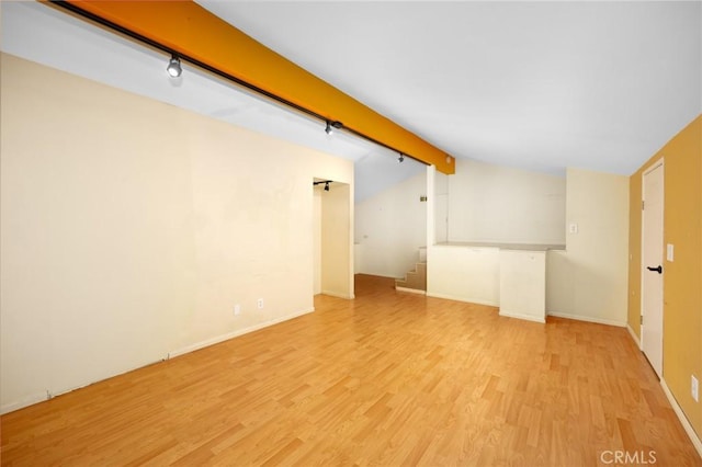 interior space featuring stairway, vaulted ceiling with beams, baseboards, and wood finished floors