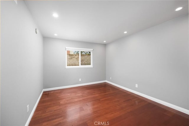 empty room with recessed lighting, wood finished floors, and baseboards