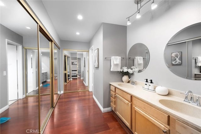 bathroom featuring recessed lighting, wood finished floors, baseboards, and a sink