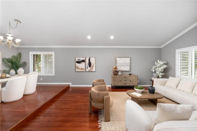 living area with wood finished floors, crown molding, baseboards, a chandelier, and vaulted ceiling