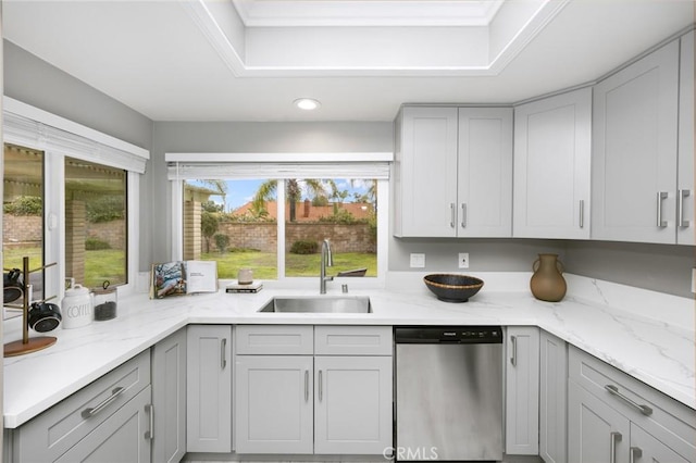 kitchen with stainless steel dishwasher, light stone counters, gray cabinetry, and a sink